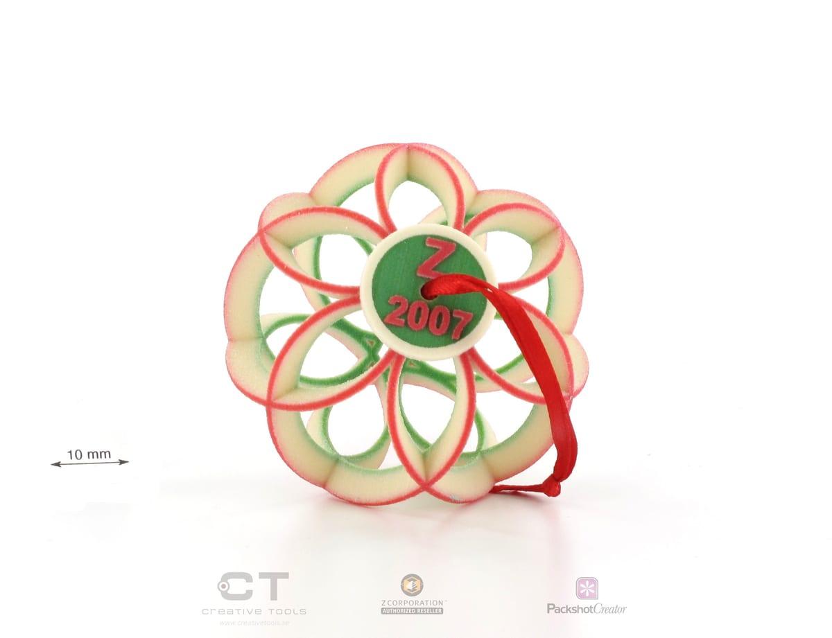 A 3D printed openwork Christmas ornament with an embossed year and a red ribbon hanger