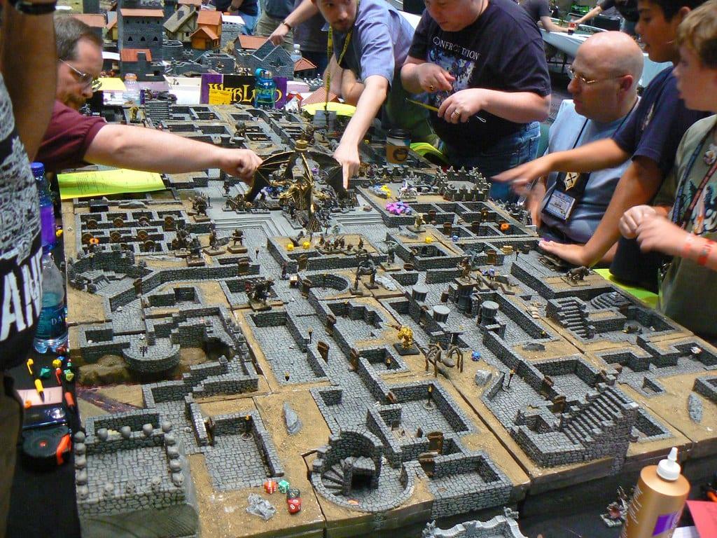 An elaborate three-dimensional dungeon laid out in modular tiles and walls with miniatures inside the rooms