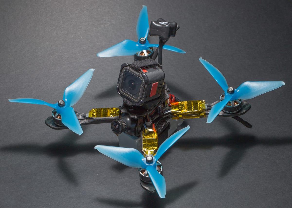 An assembled 200mm class FPV quadcopter with a carbon fibre frame, action camera and blue tri-blade propellers