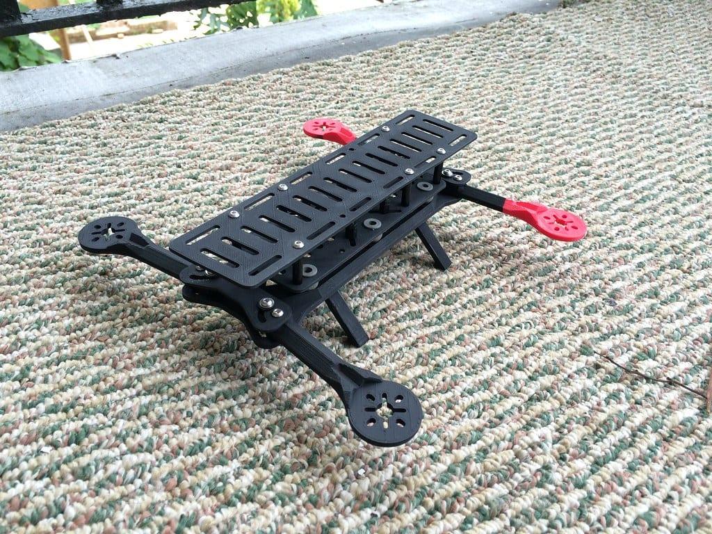 A bare 3D printed quadcopter frame with black printed arms and red printed motor mounts