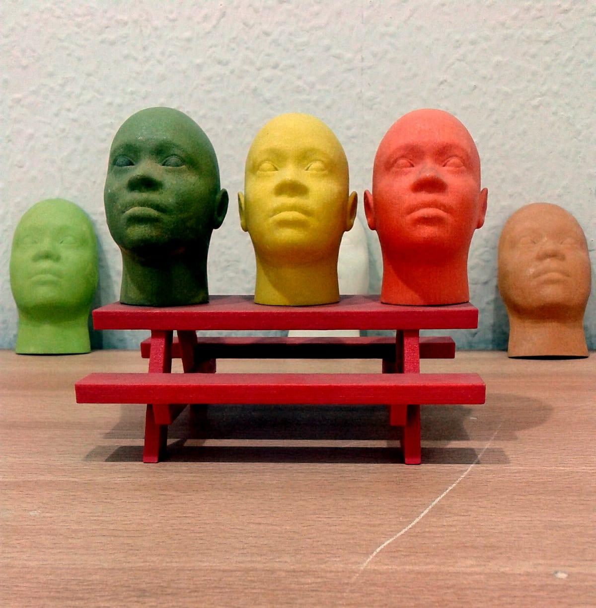 Several 3D printed model heads in different colours and sizes on a table