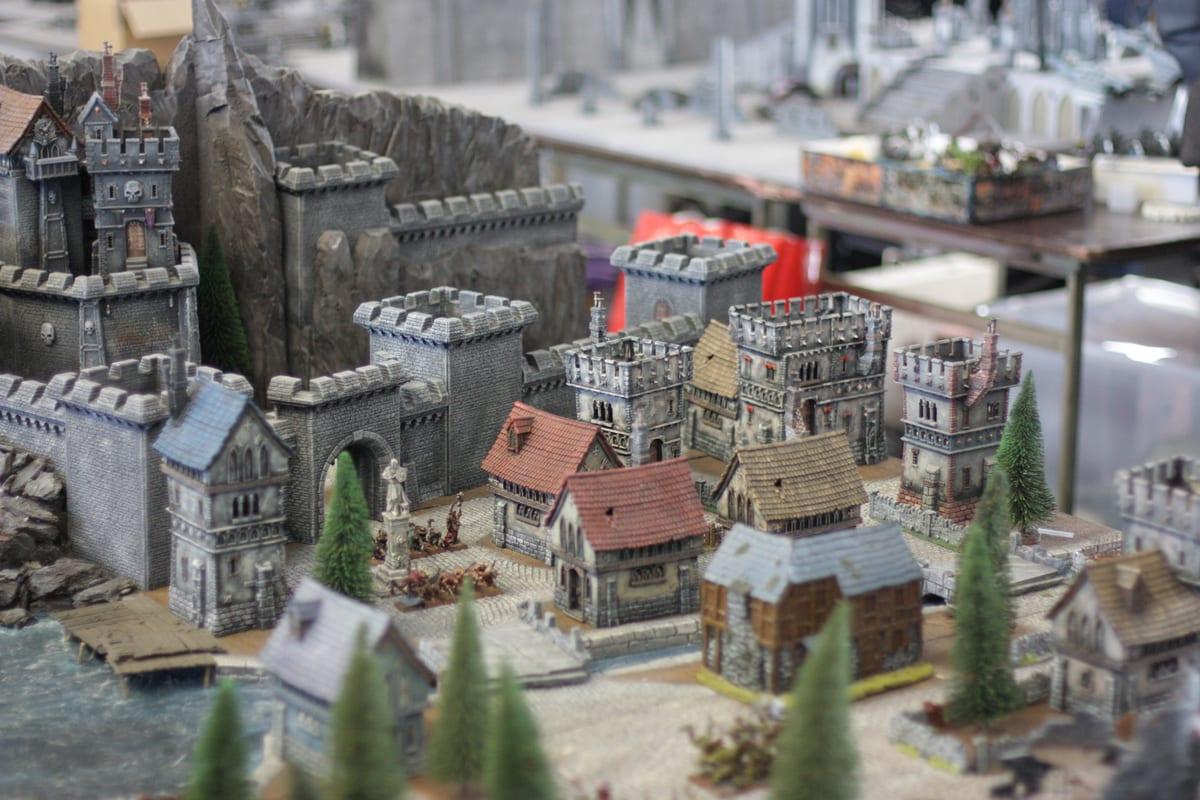 A three-dimensional fantasy wargaming table with sculpted hills, buildings and trees at a gaming festival