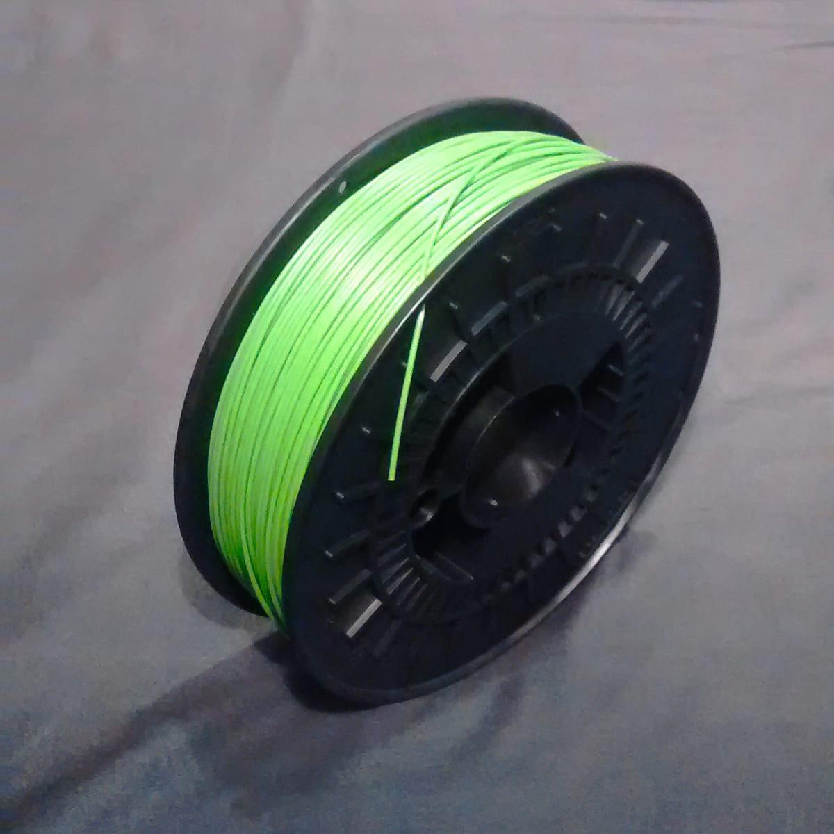 A spool of bright green ABS filament on a black plastic reel