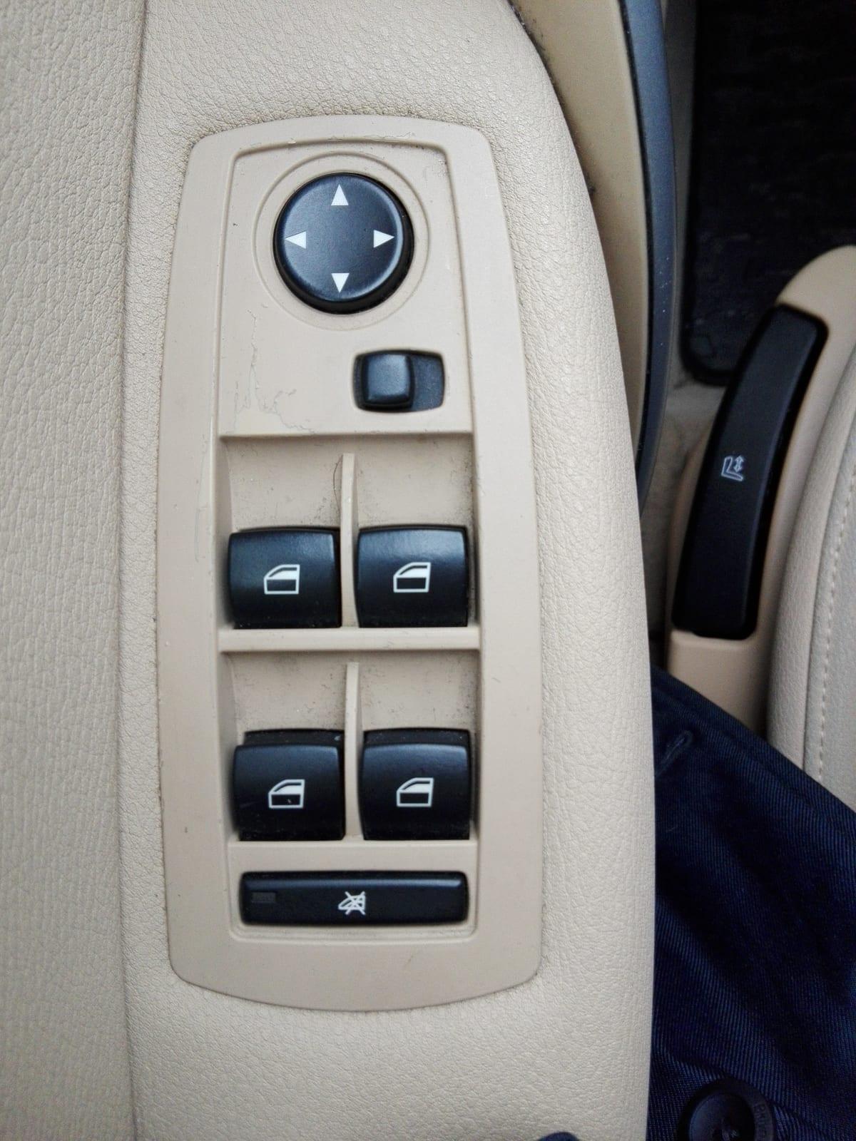 Beige plastic switch bezel set into a car door card, holding four window switches and a mirror adjuster