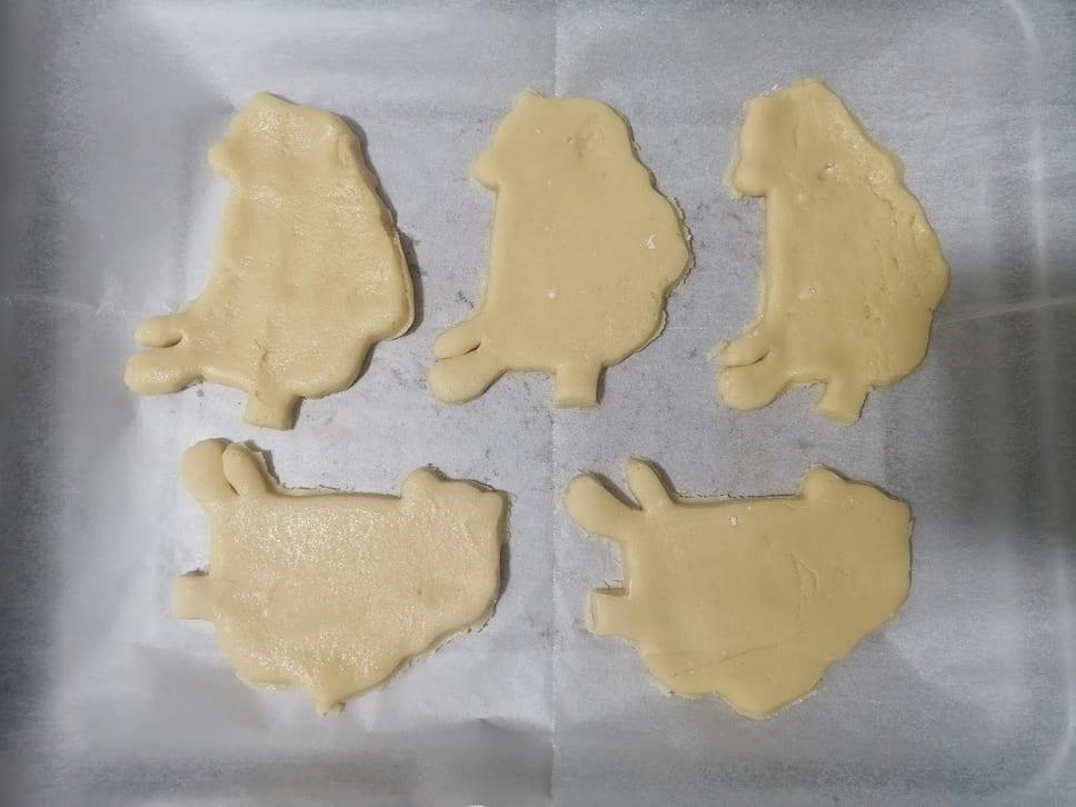 Raw cookie dough cut into a custom shape with a 3D printed cutter, on baking parchment