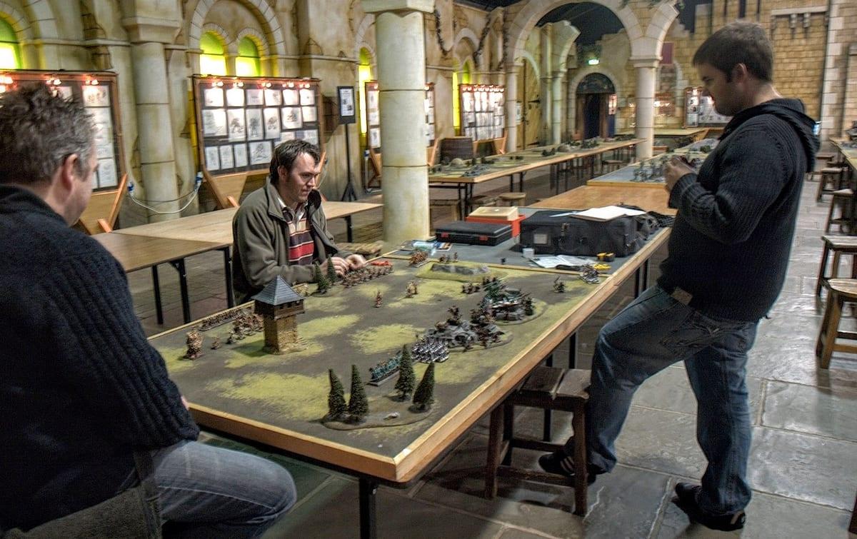 Players gathered around a wargaming table covered in miniatures and terrain