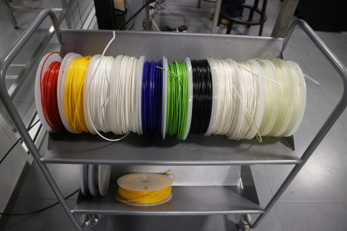 Trolley loaded with a dozen spools of 3D printer filament in red, yellow, white, blue, green, black and natural