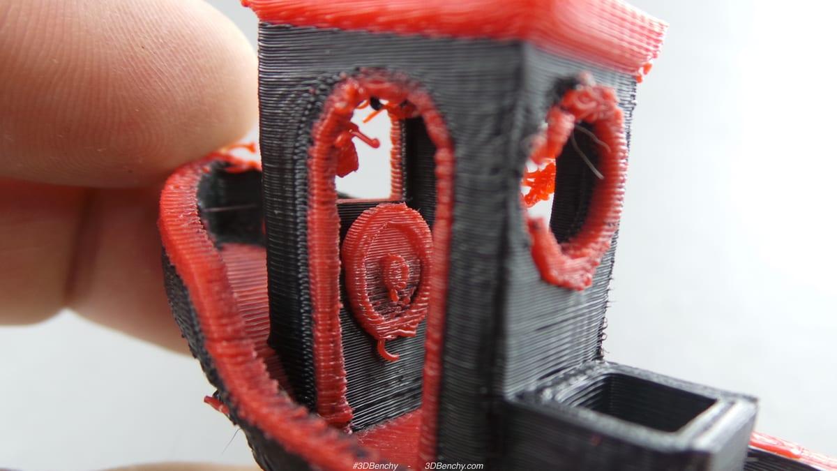 Close-up of a red and black two-colour 3D printed calibration boat held in a hand