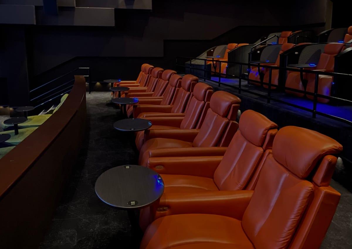 Rows of orange leather recliner seats in a cinema auditorium