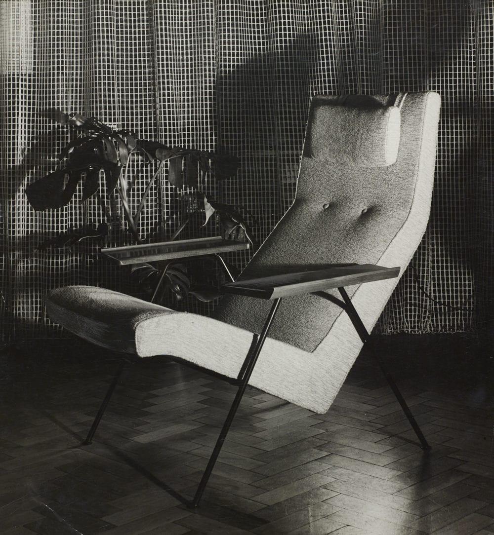 Black and white photograph of a 1952 upholstered reclining chair with a slim steel frame and wooden armrests