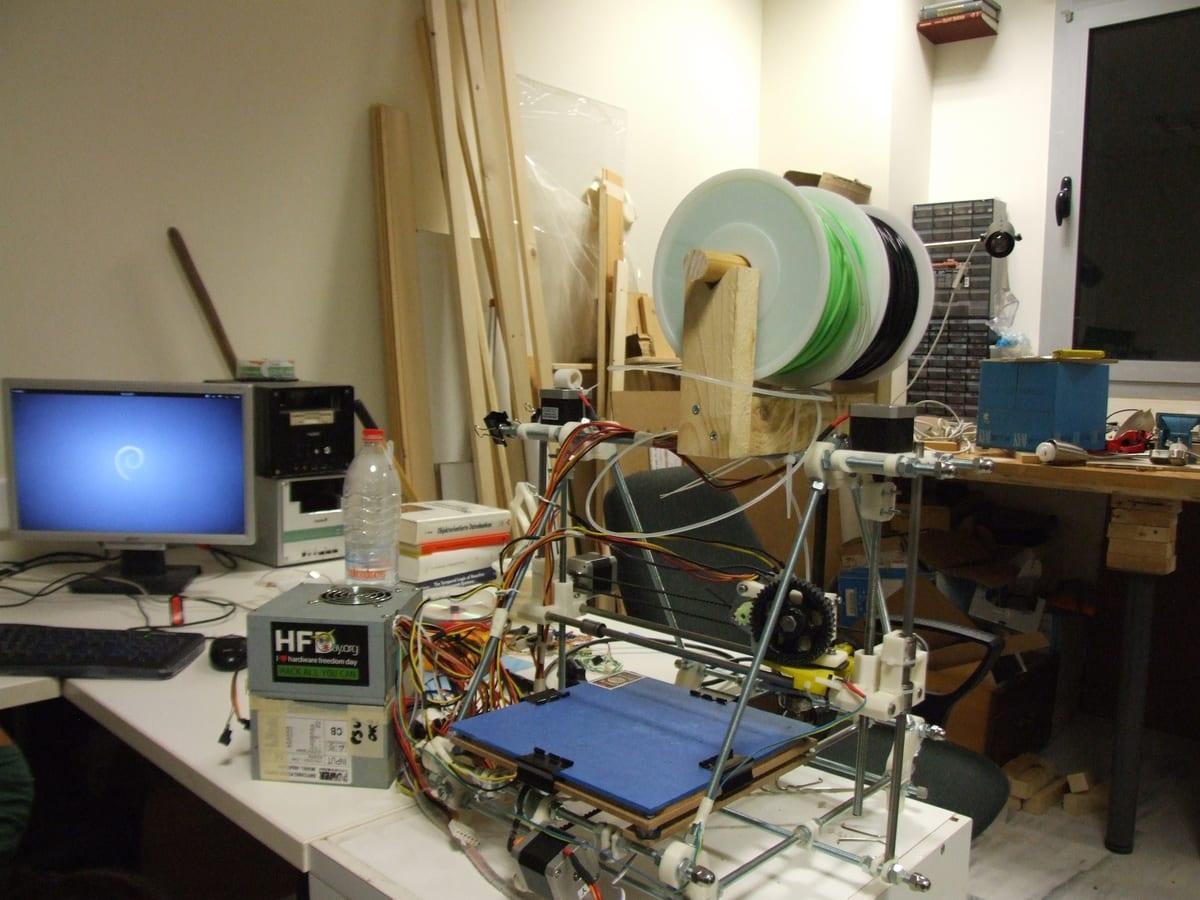 A self-built open-frame 3D printer on a bench in a shared workshop