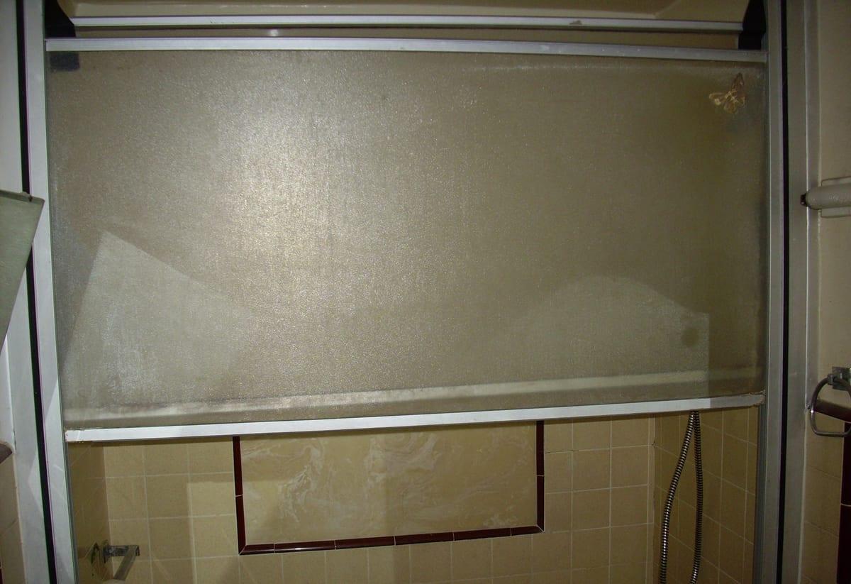 A framed glass shower door in a tiled bathroom