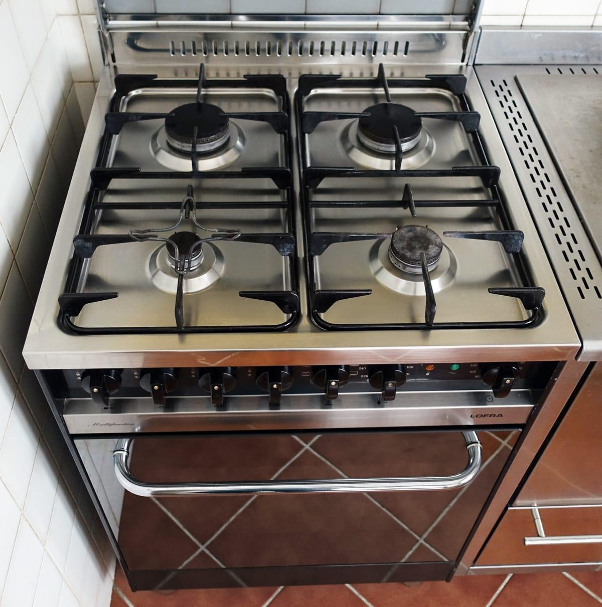 A gas cooking range with a row of control knobs on the front panel