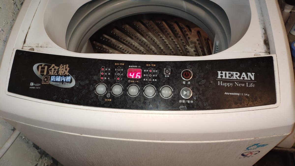 Close-up of the control panel on a top-loading washing machine showing push buttons, indicator lights and a digital timer readout