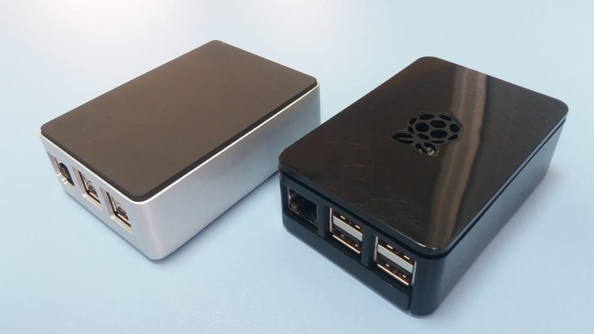 Two moulded plastic Raspberry Pi cases, one silver and one black, showing USB and Ethernet port cutouts along one side