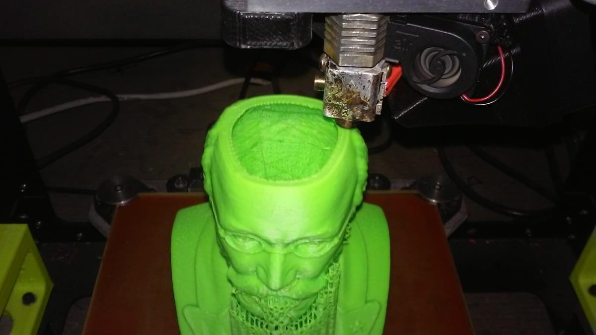 A hollow bust printing in bright green ABS filament on an open-frame 3D printer